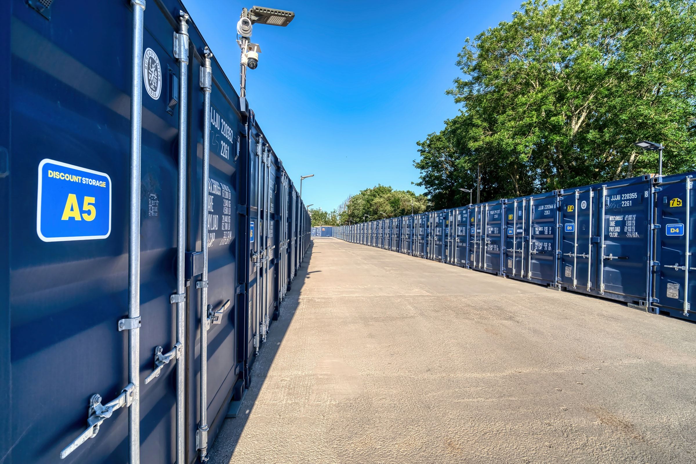 A Discount Storage container marked unit A5 with a CCTV camera mounted on the lighting column above the access lane